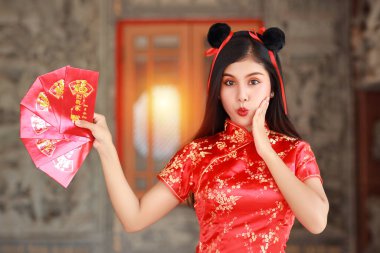 Kırmızı Çinli güzel bir kadın geleneksel Cheongsam Qipao 'nun kırmızı zarf ya da heyecan verici duyguları olan herhangi bir Pao' nun jesti, mesaj eve girerken iyi şanslar demektir (Çin yeni yılı).)
