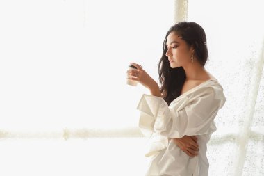 Beyaz tişörtlü Asyalı kadın sanatçıyı kapatır kahve içerken ve kalemle resim çizerken rahatlarken (kadın yaşam tarzı konsepti))