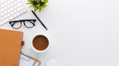 Üzerinde bilgisayar ve ofis malzemeleri olan beyaz manzaralı ahşap ofis masası. Boş defter, klavye, yeşil yaprak ve kahve fincanı olan düz bir çalışma masası. Reklam içeriğiniz için alanı kopyalayın.