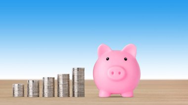 İş yatırımları ve reklam kavramı için tasarruf artışı. Mavi arka planda pembe kumbara ile büyüyen bozuk para istiflemek, büyümenin, biriktirmenin ya da para kazanmanın anlamı