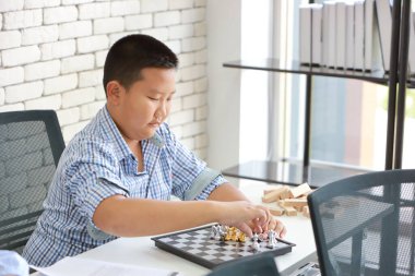 aktif ve zeki Asyalı çocuk sınıfta satranç oynuyor