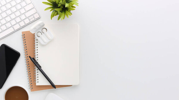 Вид сверху белый деревянный рабочий стол с компьютером и офисными принадлежностями. Плоский рабочий стол с чистым блокнотом, клавиатурой, зеленым листом и кофейной чашкой. Копирование рекламного контента.