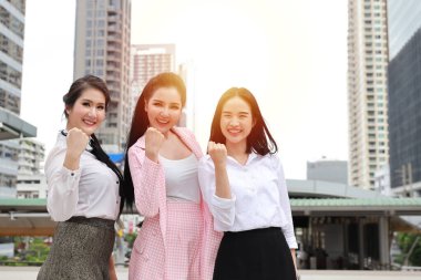 Mutlu gülümseyen Asyalı genç iş kadını resmi giysiler içinde, başarılı bir başarı sembolü gösteriyorlar başarılı ve mutlu bir gülümseme ve kentsel görünüm ile tamamlanmış