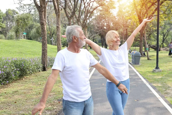 Elder caucasian couple in white shirt enjoying exercise and stretching outdoor in public park with relaxation on holiday