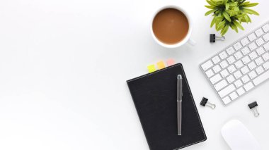 Üzerinde bilgisayar ve ofis malzemeleri olan beyaz manzaralı ahşap ofis masası. Boş defter, klavye, yeşil yaprak ve kahve fincanı olan düz bir çalışma masası. Reklam içeriğiniz için alanı kopyalayın.