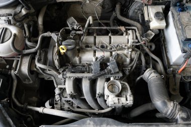 Tamirat sırasında kısmen parçalanmış modern bir arabanın motorunun üst görüntüsü. Emme manifoldu çıkarıldı, ateşleme bobinleri. Motor kirli..