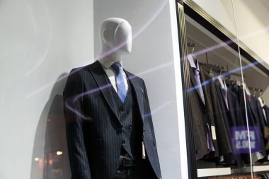 Moda mağazasının vitrininde duran manken sıkı bir takım elbise giyiyor..