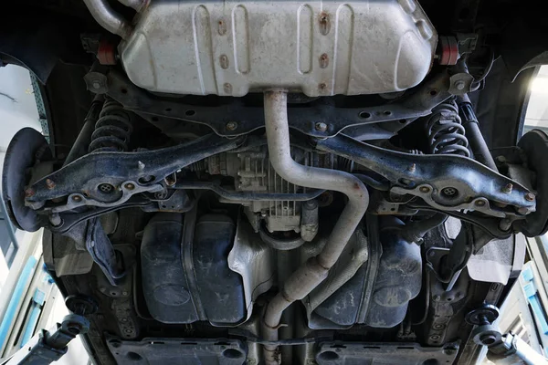 A car in a car service is lifted on a lift for repair. Bottom view of the car. Vehicle underbody, rear suspension elements and muffler.