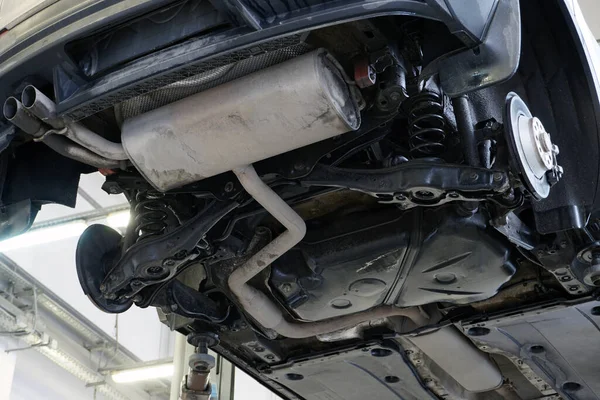 Car in a car service on a lift. Bottom view of the car. The structure and elements of the rear suspension, exhaust system. Spare parts and car service.