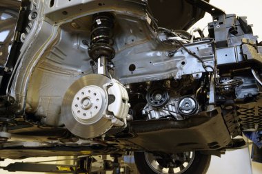 Modern bir araba kısmen tamir için parçalanmış. Ön çamurluk makineden çıkarılmış ve süspansiyonun parçaları, fren sistemi ve motorun bir kısmı görünür..