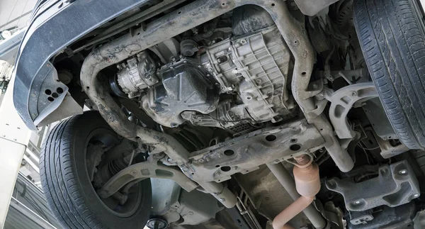 リフトの車のサービスで車 エンジン保護は機械から削除されました ギアボックス エンジントレイ エアコンコンプレッサー サスペンション部品 排気システムの一部が表示されます — ストック写真