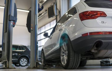 Moskova Rusya - Haziran 2021: Beyaz lüks SUV servis asansöründe bekliyor. Arka planda başka bir araba var. Arkaplan bulanık.