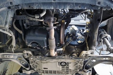 Araba servisindeki modern araba asansörde. Motorun alt görüntüsü, şanzıman kaldırıldı. Flywheel, egzoz borusu görünür. Seçili odak.