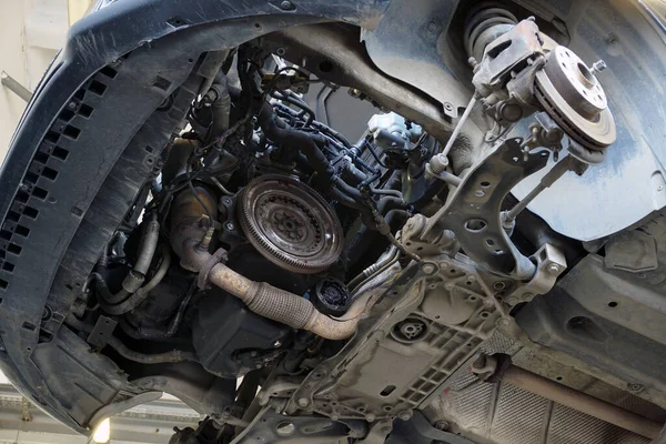 リフト上の車のサービスで近代的な車 車の中で ギアボックスは修理のために取り外された フライホイール 排気システムの要素が表示されます 選択されたフォーカス — ストック写真