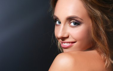 Koyu arka plan üzerinde kıvırcık uzun saçlı güzel kadın