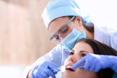 Kadın dişçi hastalarının dişlerinde çalışıyor.