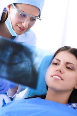 Kadın dişçi hastalarının dişlerinde çalışıyor.