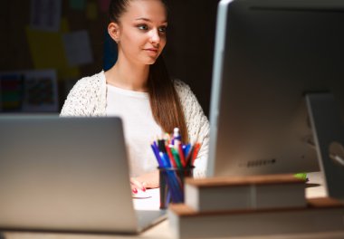 Ofiste çalışan genç bir kadın, masada oturuyor.