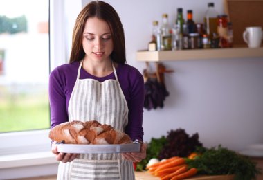 Genç bir kadın mutfağında lezzetli taze ekmek tutuyor.