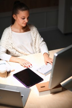Ofiste çalışan genç bir kadın, masada oturuyor.