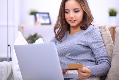 Bilgisayarı ve kredi kartıyla gülümseyen güzel bir kadın.