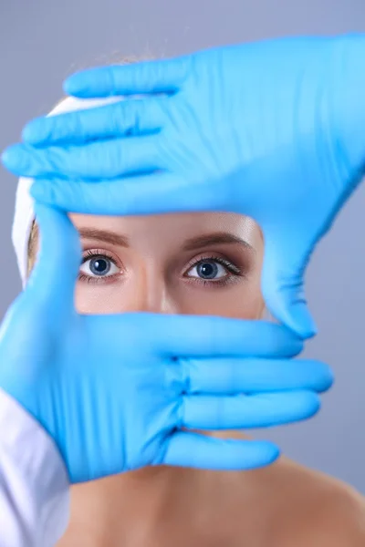 Las manos de un cirujano tocando una cara femenina — Foto de Stock