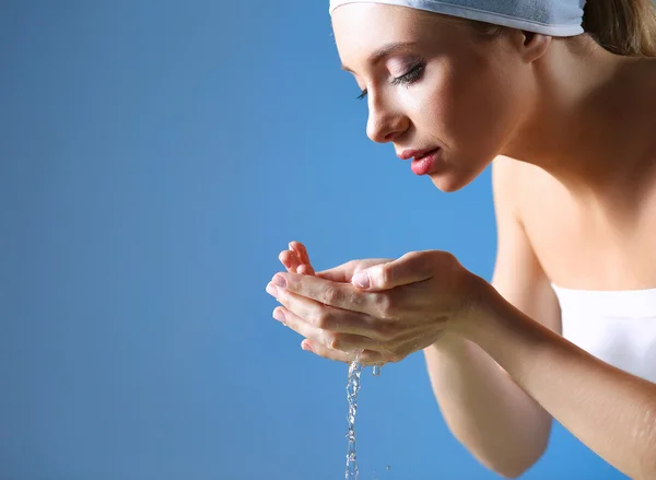 Mujer joven lavándose la cara con agua clara —  Fotos de Stock