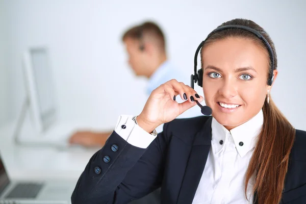 Gelukkig vrouwtje draagt een headset en zit op het bureau — Stockfoto