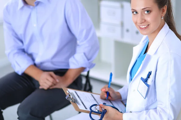 Médecin femme assise avec un patient masculin au bureau — Photo