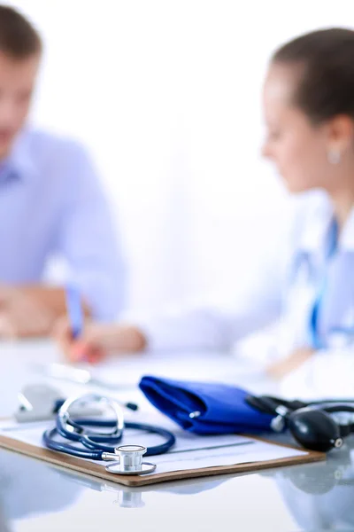 Doktorka sedí s mužským pacientem u stolu — Stock fotografie