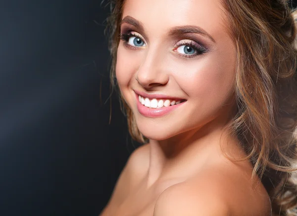 Beautiful woman with curly long hair on dark background — Stock Photo, Image