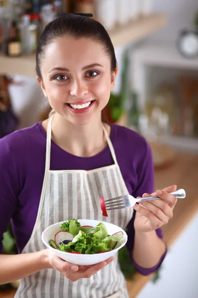 Jovem mulher comendo salada fresca na cozinha moderna — Fotografia de Stock