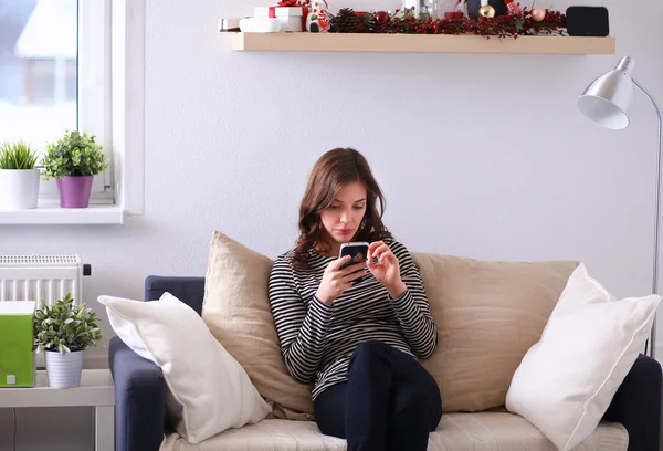 Ładna dziewczyna za pomocą smartfona na kanapie w domu w salonie — Zdjęcie stockowe