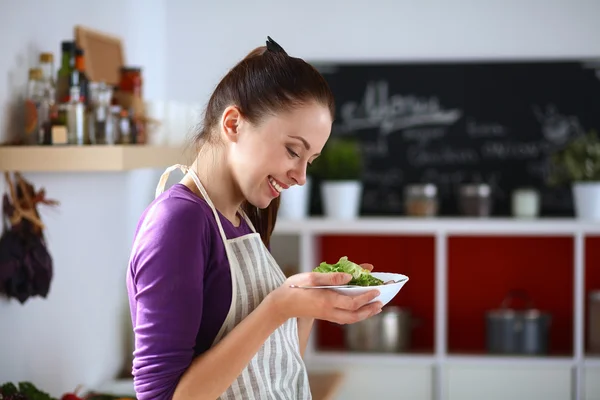 Junge Frau isst frischen Salat in moderner Küche — Stockfoto