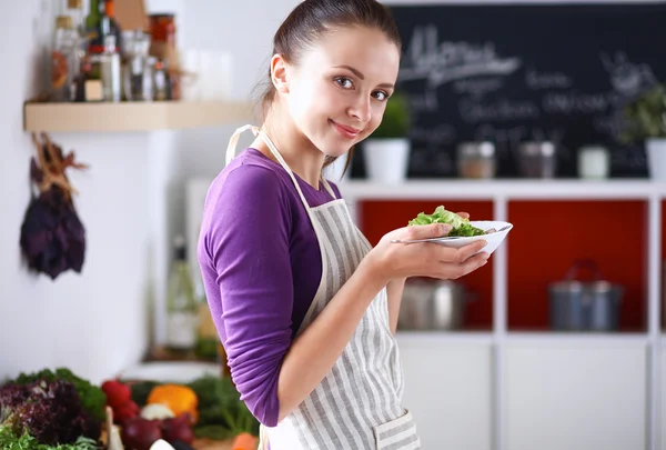 Jovem mulher comendo salada fresca na cozinha moderna — Fotografia de Stock