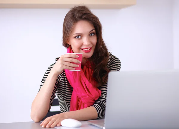 Porträtt av leende affärskvinna med kaffe kopp framför laptop — Stockfoto