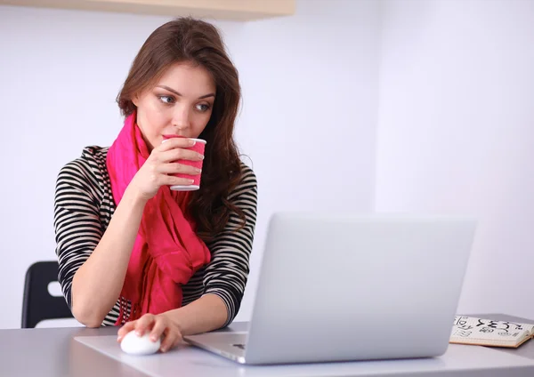 Porträtt av leende affärskvinna med kaffe kopp framför laptop — Stockfoto