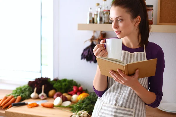 Junge Frau liest Kochbuch in der Küche und sucht Rezept — Stockfoto