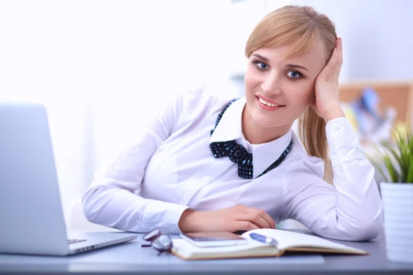 Portrait of  businesswoman sitting at  desk with a laptop Stock Picture