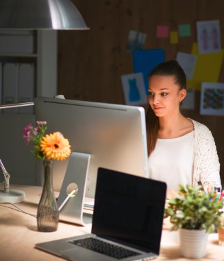 Ofiste çalışan genç bir kadın, masada oturuyor.