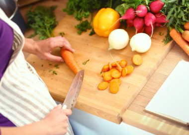 Mutfakta sebze doğrayan genç bir kadın.