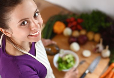 Genç kadın modern mutfakta taze salata yiyor.