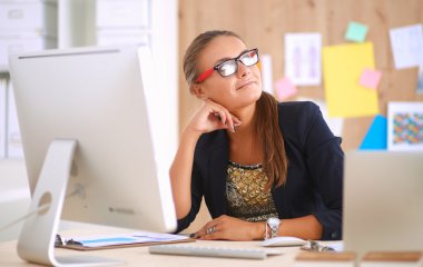 Moda tasarımcıları stüdyoda çalışıyor. Masanın üzerinde oturuyorlar.