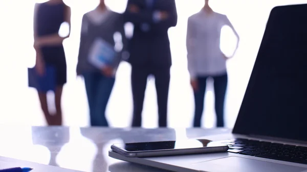 Laptop  computer on  desk ,  businesspeople standing in the background — Stock Photo, Image