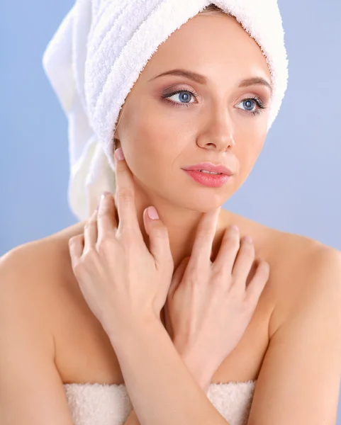 Mooie vrouw met een handdoek op haar hoofd op een grijze achtergrond — Stockfoto