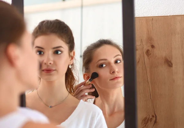 Schöne Mädchen, die in den Spiegel schauen und Kosmetik mit einem großen Pinsel anwenden — Stockfoto