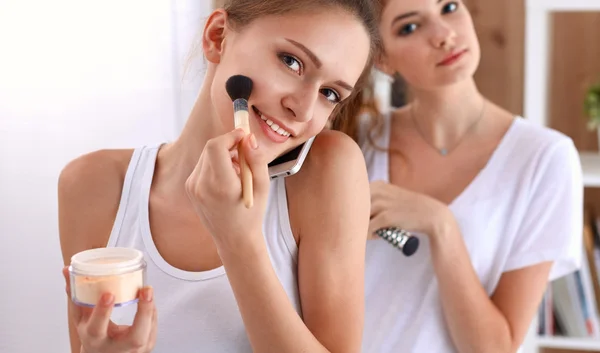 Piękne dziewczyny patrzące w lustro i nakładające kosmetyki dużą szczotką — Zdjęcie stockowe