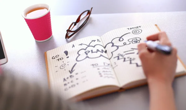 Young woman writes to diary on a white table — Stock Photo, Image