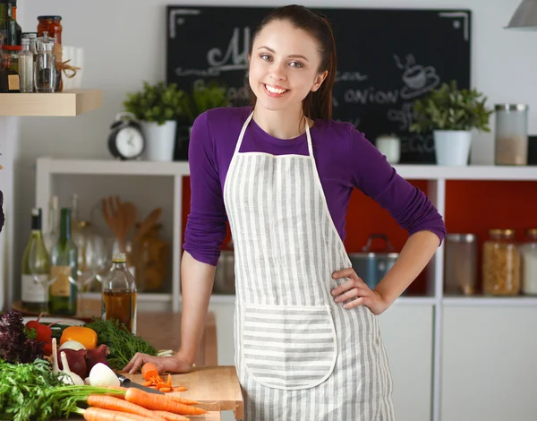 Mujer joven de pie en su cocina cerca del escritorio con bolsas de compras —  Fotos de Stock