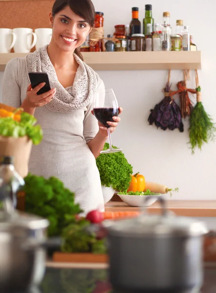 Mujer joven cortando verduras en la cocina, sosteniendo una copa de vino —  Fotos de Stock